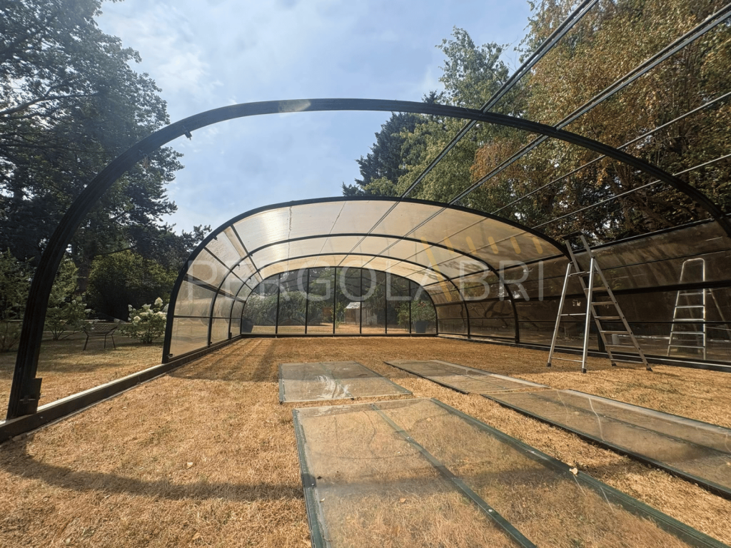 Dépose d'une plaque de polycarbonate alvéolaire sur un abri de piscine.