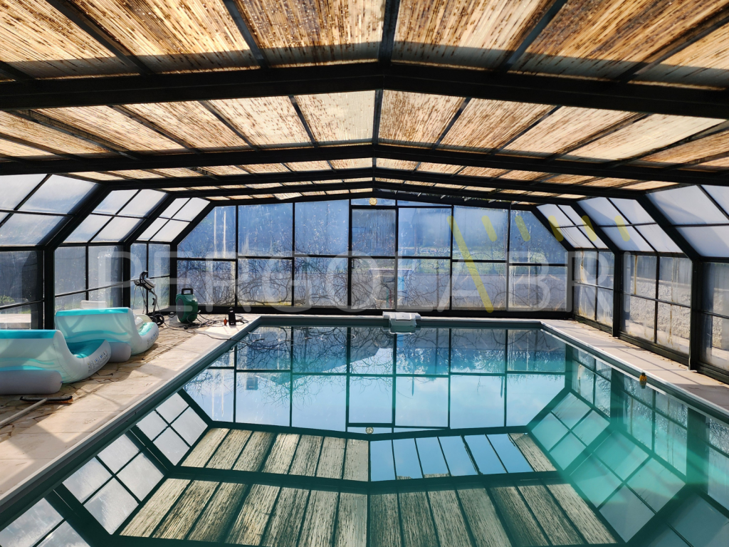 Plaques de toiture jaunies et noircies par le temps sur un abri de piscine haut