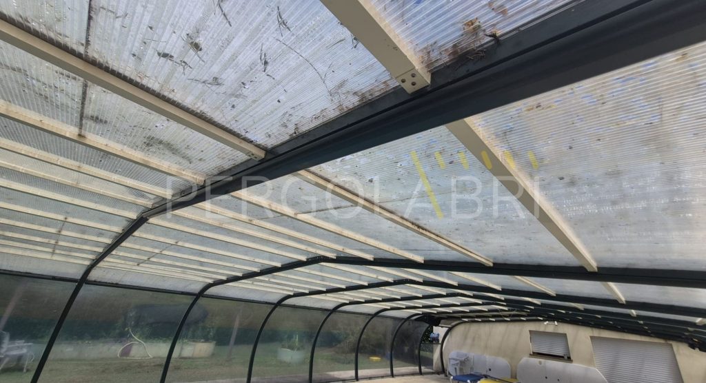 Plaques de polycarbonate jaunies et fragilisées sur la toiture d’un abri de piscine