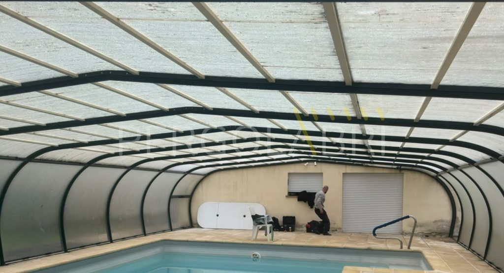 Plaques de polycarbonate jaunies et fragilisées sur la toiture d’un abri de piscine